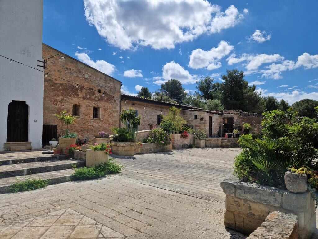 La corte in pietra della masseria con piante e fiori